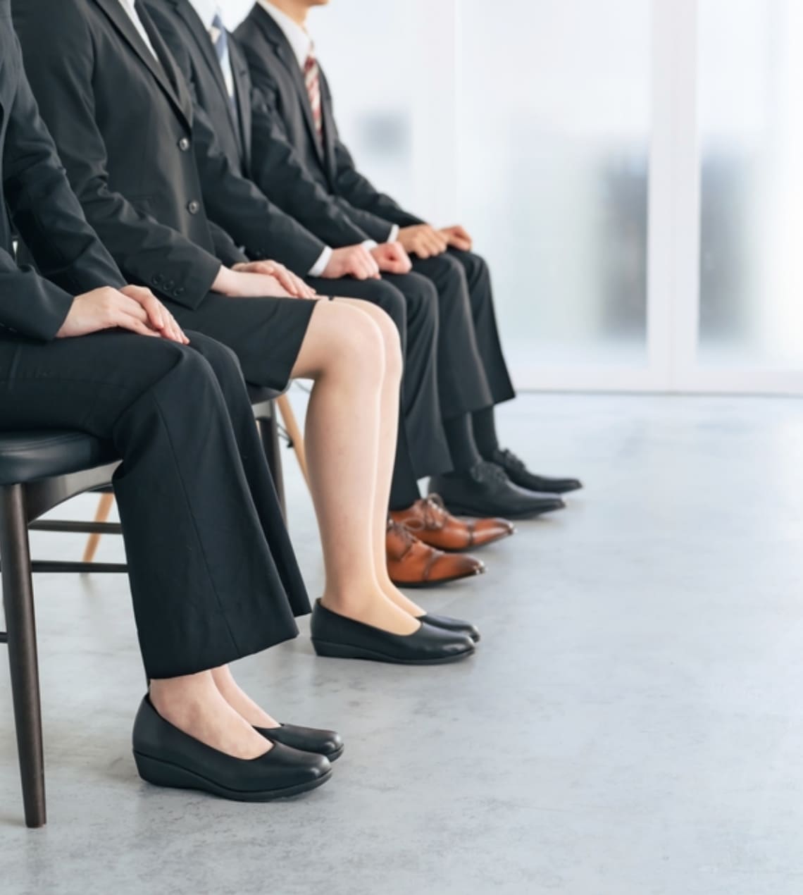 入社式でスーツを着た男女が座っています。